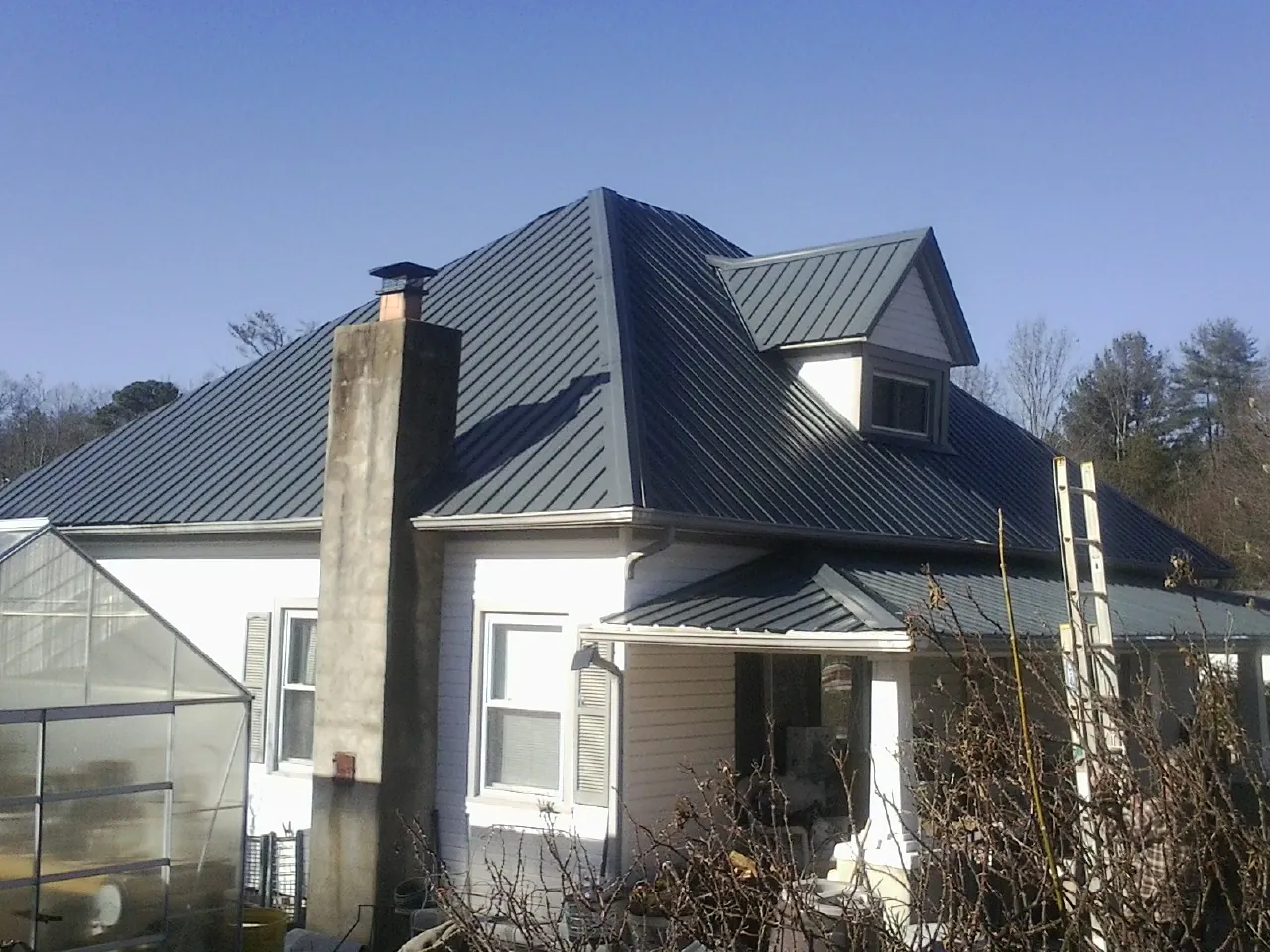 Dark blue standing seam metal roof on a white farmhouse with dormer — Slate & Tile Roof Repair by Roofing Brothers in Red Bud