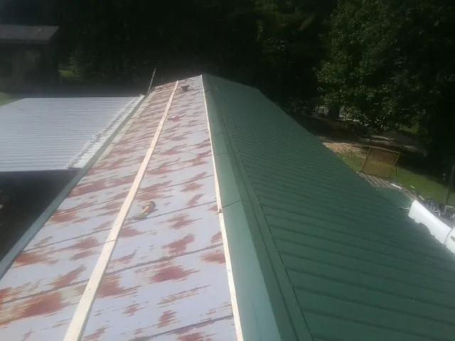 Old rusted panels beside newly installed green metal roofing — Wind Damage Roof Repair by Roofing Brothers in Red Bud