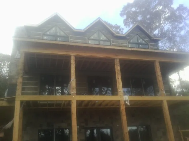 Dormers and porch framing on a large log home under construction — Roof Coating work by our crew in Red Bud