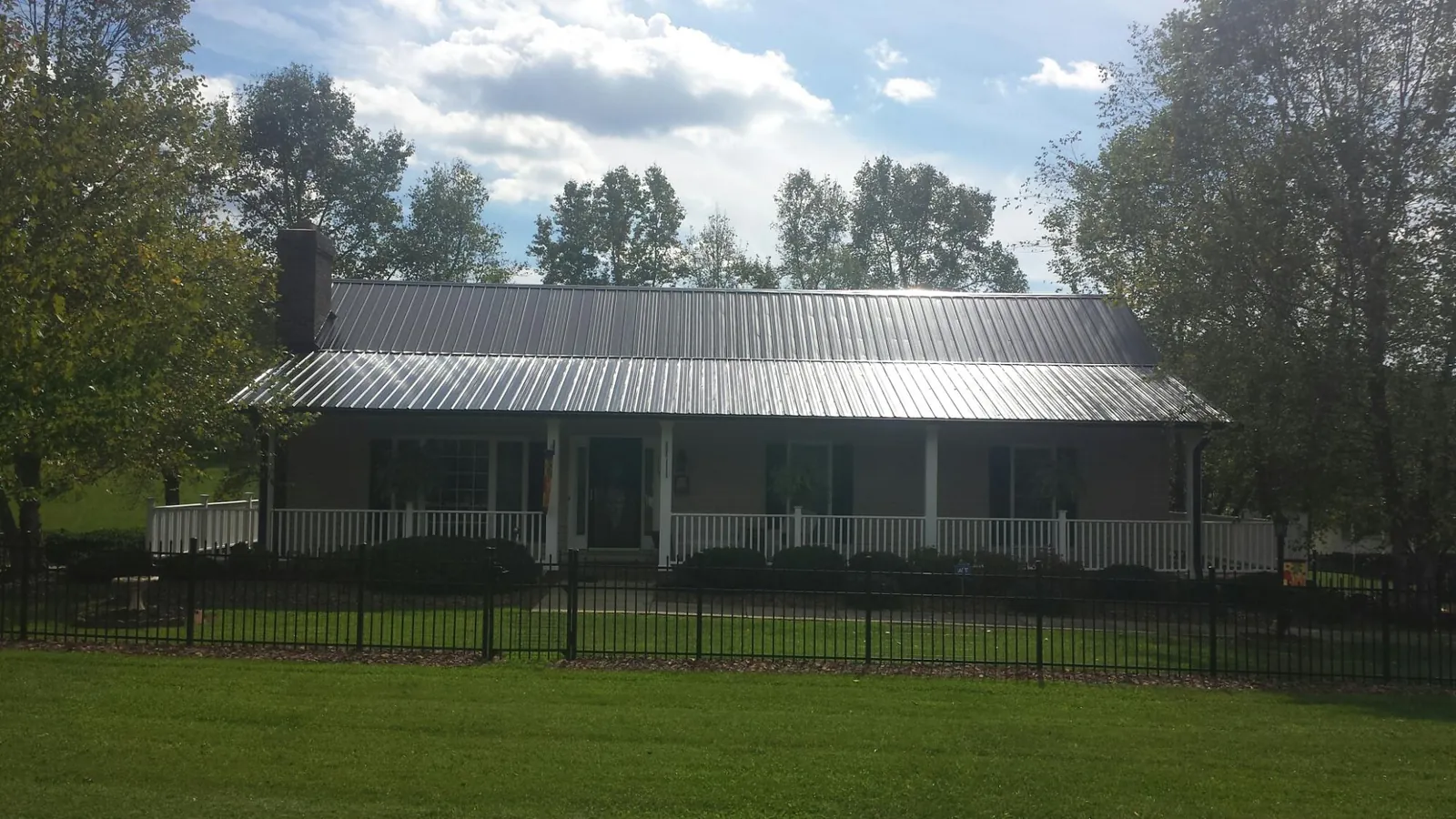 Gray metal roof on a brick ranch with a full width front porch — Gutter Guard Installation work by our crew in Red Bud