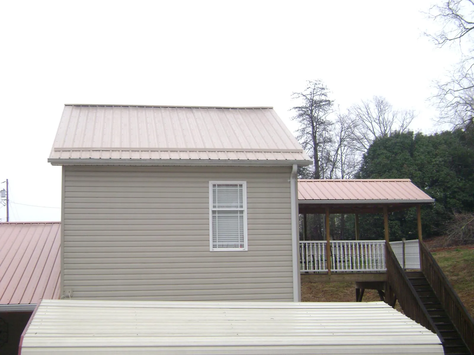 Tan metal roofs on a two story addition and attached porch, from a Roof Replacement job in Red Bud