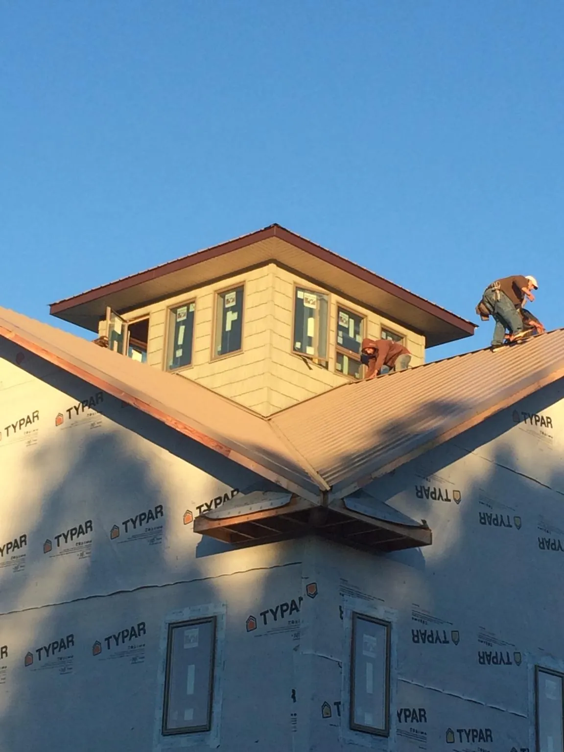 Roofers working around a rooftop cupola on a new metal roof at sunset — Roof Waterproofing in Red Bud by Roofing Brothers